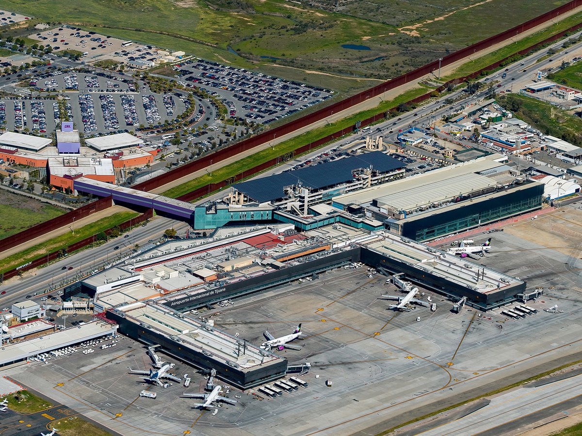 An aerial image of Tijuana Airport, a sprawling, economic hub of the city, with multiple passenger terminals connected to the Cross Border Express sky bridge, providing easy access for global travelers.