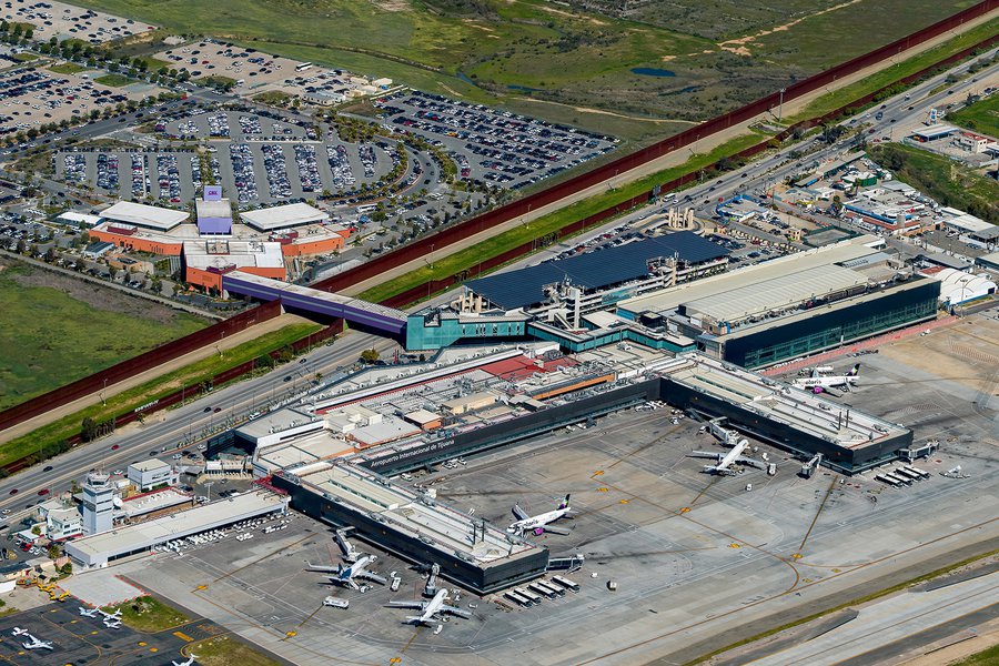An aerial image of Tijuana Airport, a sprawling, economic hub of the city, with multiple passenger terminals connected to the Cross Border Express sky bridge, providing easy access for global travelers.