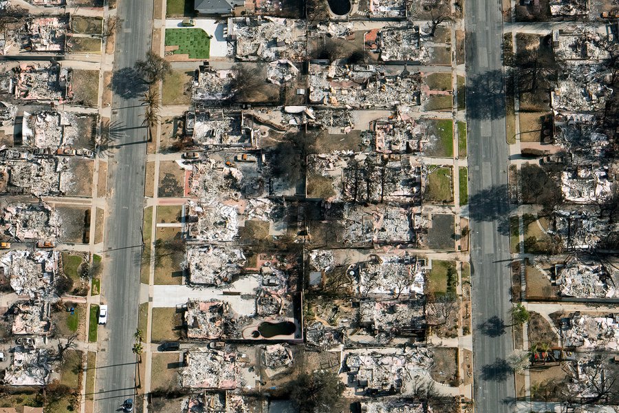 A top-down view of Altadena shows two parallel streets dividing the frame, with the ashen remains of destroyed houses on either side, illustrating the extent of the Eaton Fire's damage.
