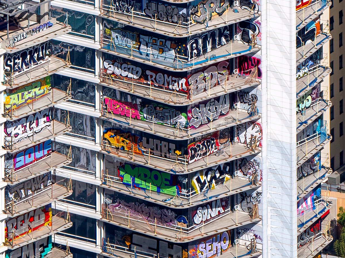 A close-up aerial view showing vibrant graffiti art on the abandoned Oceanwide Plaza towers in Downtown Los Angeles, California.