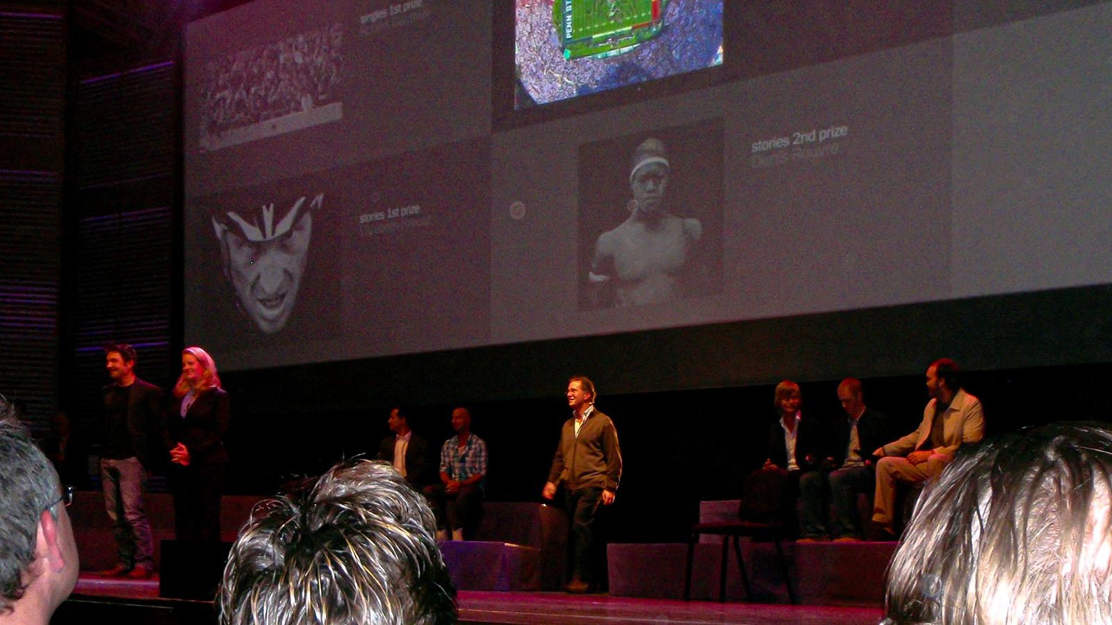 Press photo Mark Holtzman walking onstage in front of his award-winning photograph of the B-2 Bomber over the Rose Bowl at the 2010 Awards Ceremony in Amsterdam, Netherlands