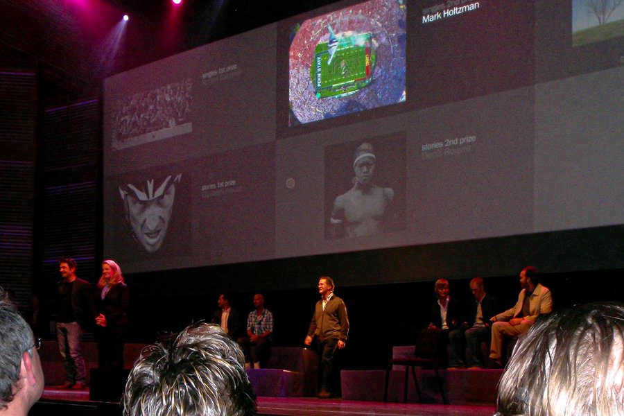 Press photo Mark Holtzman walking onstage in front of his award-winning photograph of the B-2 Bomber over the Rose Bowl at the 2010 Awards Ceremony in Amsterdam, Netherlands