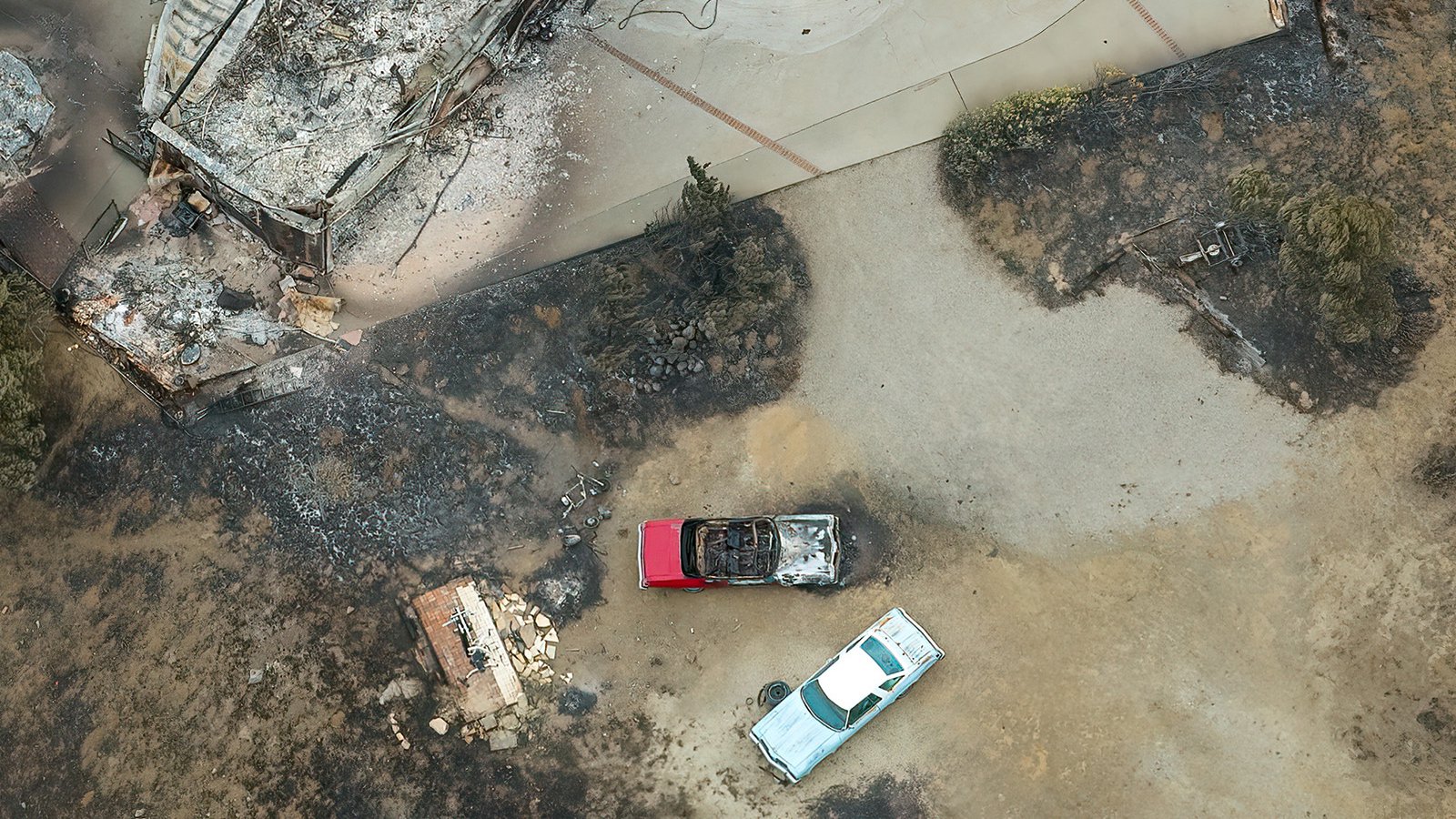 In this aerial photo of the Arroyo Sequit after the Woolsey Fire, a home is reduced to ash and rubble as two classic cars lay charred in its wake.