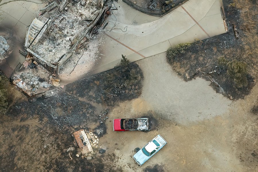 In this aerial photo of the Arroyo Sequit after the Woolsey Fire, a home is reduced to ash and rubble as two classic cars lay charred in its wake.