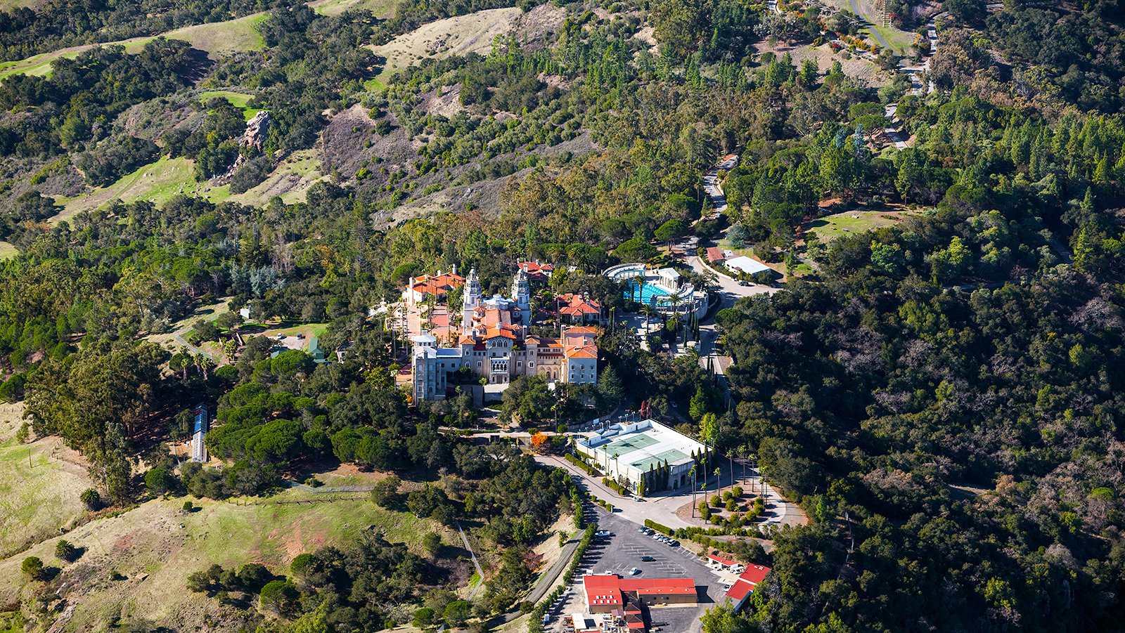 An aerial photograph of Hearst Castle showcases the grandiose and magnificent estate, located on a hilltop overlooking the Pacific Ocean in San Simeon, California