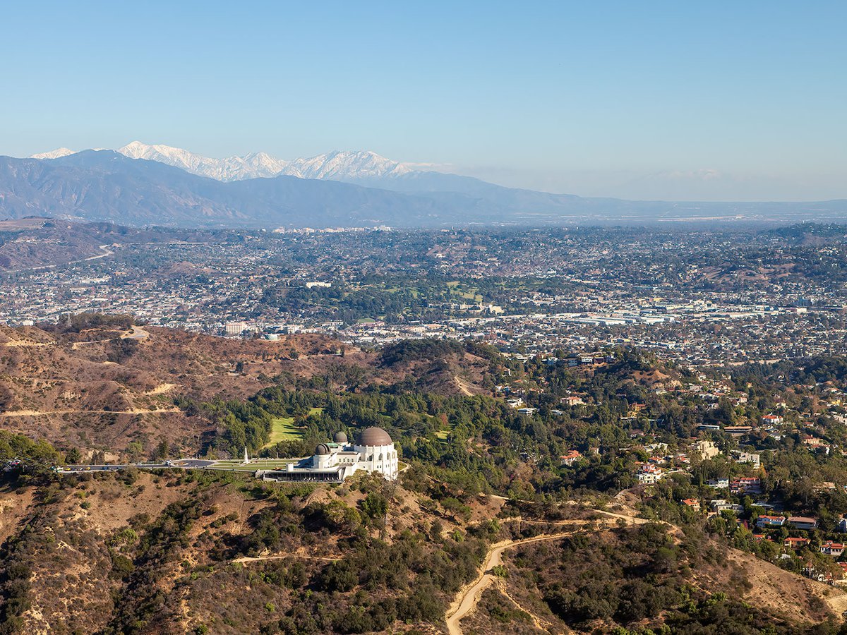 Griffith Observatory, perched atop Griffith Park, with snow-capped peaks of the San Gabriel Mountains in the background