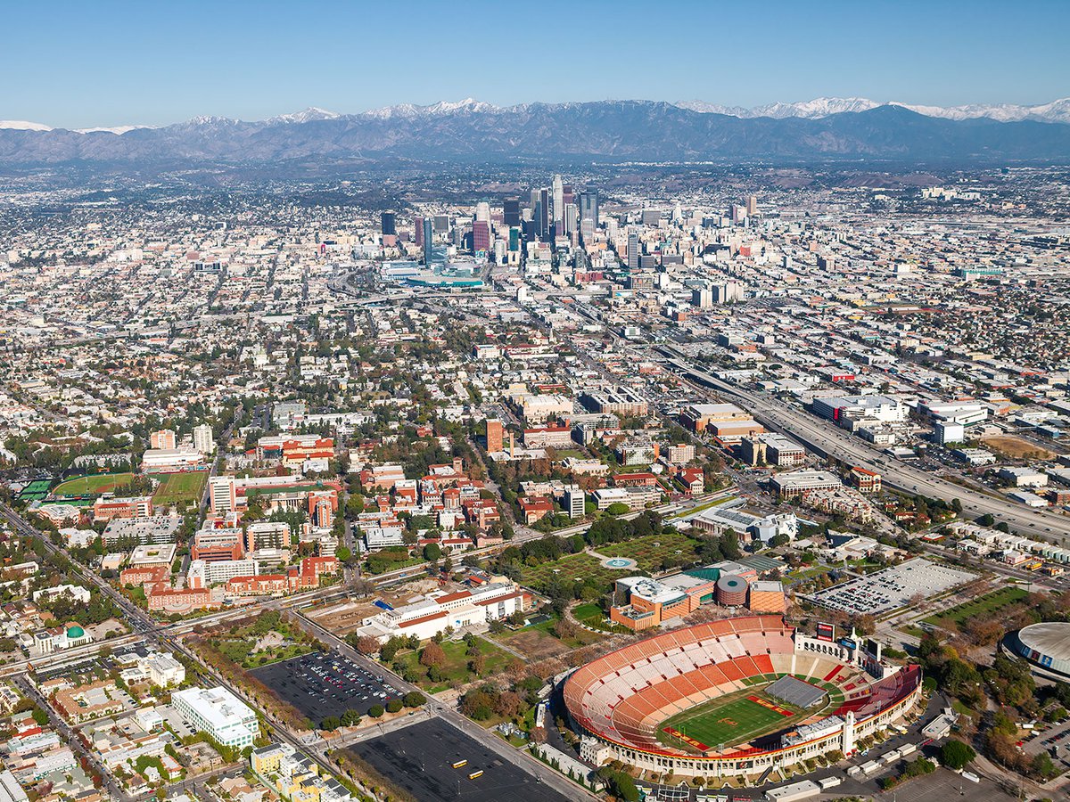 Aerial blog image of USC and the Los Angeles Memorial Coliseum with Downtown Los Angeles and snow-capped mountains in the background